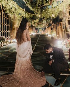 a man kneeling down next to a woman in a wedding dress