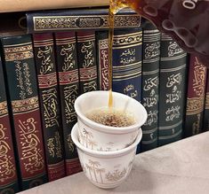 a person pouring tea into two cups in front of books