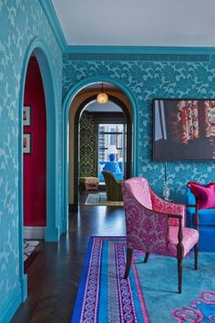 a living room with blue walls and pink chairs in the center, along with a rug on the floor