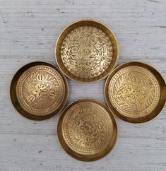 four brass plates sitting on top of a wooden table