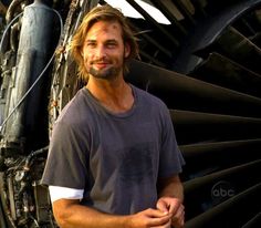 a man standing in front of an airplane's engine and looking at the camera