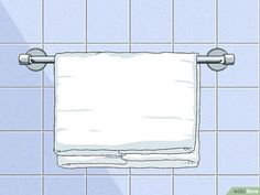 a white towel hanging on the wall above a toilet paper dispenser in a tiled bathroom