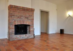 an empty living room with brick fireplace and tile flooring in the center, surrounded by white walls