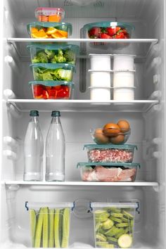 an open refrigerator filled with lots of different types of vegetables and fruit in plastic containers