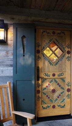 a wooden chair sitting in front of a door next to a light on the side of a building