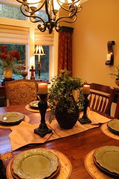 a dining room table with plates and candles on it