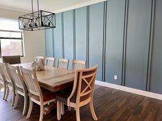 a dining room table and chairs with blue striped walls in the backround area