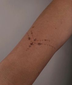 a woman's arm with a cross tattoo on it and dots in the middle