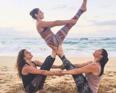 three women are doing yoga on the beach