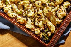 a tray filled with lots of food on top of a wooden table next to a blue napkin