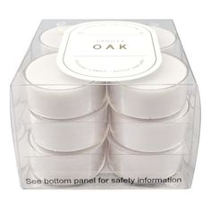 six white candles in a clear box with the words, oak on it's side