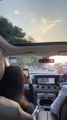 two people sitting in the driver's seat of a car looking at their cell phones