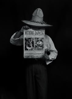 a man in a hat holding up a newspaper