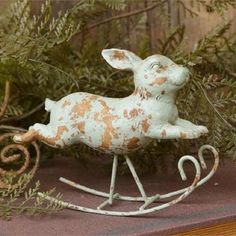 a white and brown rabbit sitting on top of a wooden sleigh next to plants