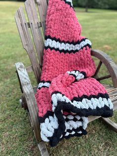 a crocheted blanket sitting on top of a wooden rocking chair in the grass