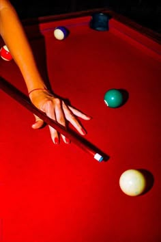 a woman's hand on the edge of a pool table with balls around it