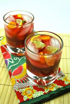 two glasses filled with drinks sitting on top of a table next to a place mat