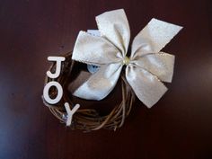 a white bow sitting on top of a wooden table with the word joy spelled in it