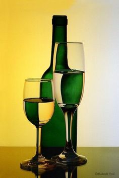 two wine glasses sitting next to a bottle on top of a table with a yellow wall in the background