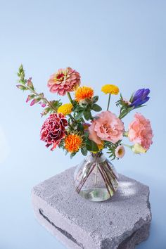 a vase filled with colorful flowers sitting on top of a rock