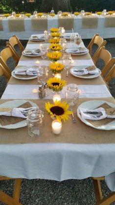 the table is set with sunflowers and place settings for two people to sit at