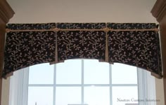 a window with a black and gold valance hanging over it's windowsill