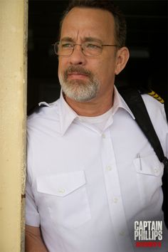 a man wearing glasses and a white shirt is standing in front of a door with his back to the camera