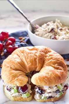 a cranberry chicken salad sandwich on a roll with a bowl of coleslaw in the background