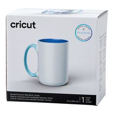 a white and blue coffee mug sitting in front of a box with its lid open