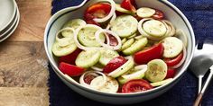 a bowl filled with sliced up vegetables on top of a blue cloth next to a fork