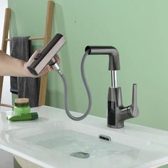 a person is using a hair dryer to clean a sink faucet in a green bathroom