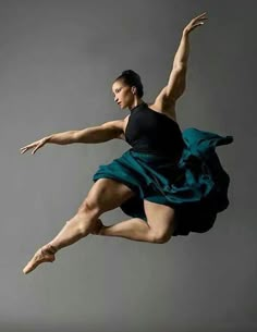 a man in black shirt and blue skirt doing a dance move with one leg up