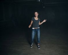 a woman is standing in the dark with her hand out and pointing to something on the floor