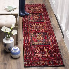 a large red rug on the floor next to a vase with flowers