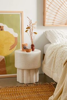 a bedroom with a white bed and a painting on the wall next to a small table