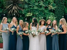 a group of women standing next to each other in front of a green plant wall