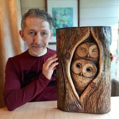 a man sitting at a table with an owl carving on it