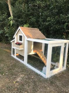 a chicken coop with stairs leading up to the roof and door open in front of some trees