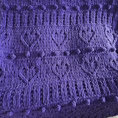 a purple crocheted blanket sitting on top of a wooden table