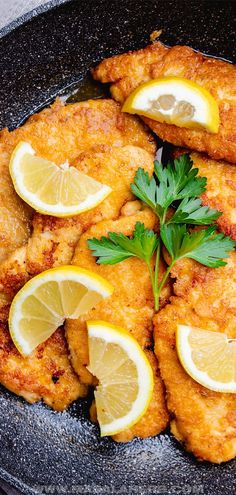 fried chicken with lemons and parsley in a skillet