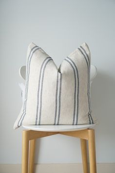 a white and blue striped pillow sitting on top of a wooden stool