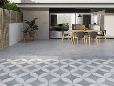 an outdoor dining area with concrete flooring and circular tiles on the ground, as well as potted plants