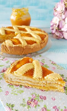 two pieces of pie sitting on top of a table next to flowers and a jar of honey