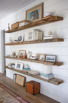 some shelves with pictures and other items on them in a room that is painted white