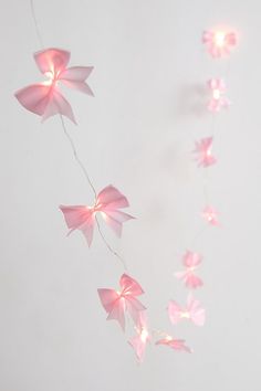 some pink paper flowers are hanging from a string on a white wall and light up the room