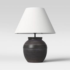 a table lamp with a white shade on it's base and a black vase