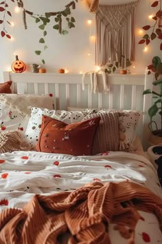 a white bed topped with lots of pillows next to a wall covered in pumpkins