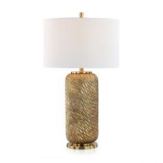 a gold table lamp with a white shade on the base and a light in front of it