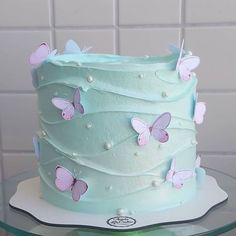 there is a blue cake with pink butterflies on the top and white icing around it