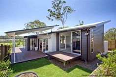 a house that is in the grass with a deck and some windows on top of it